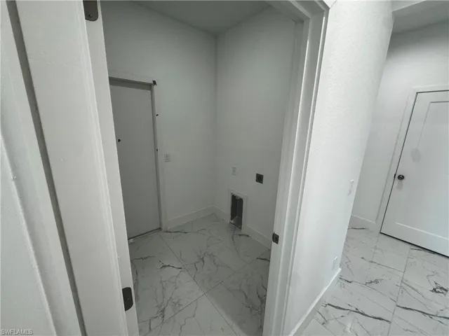 Laundry room doorway with marble finish floor, baseboards, and laundry area