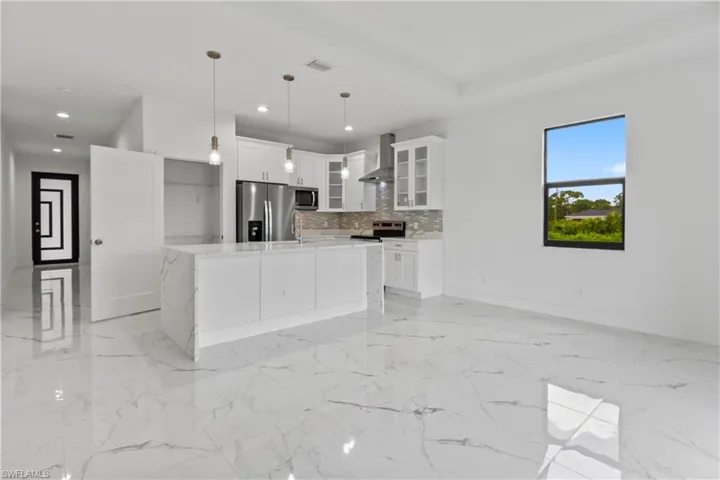 Kitchen featuring light marble finish floors, stainless steel appliances, wall chimney exhaust hood, light countertops, and recessed lighting