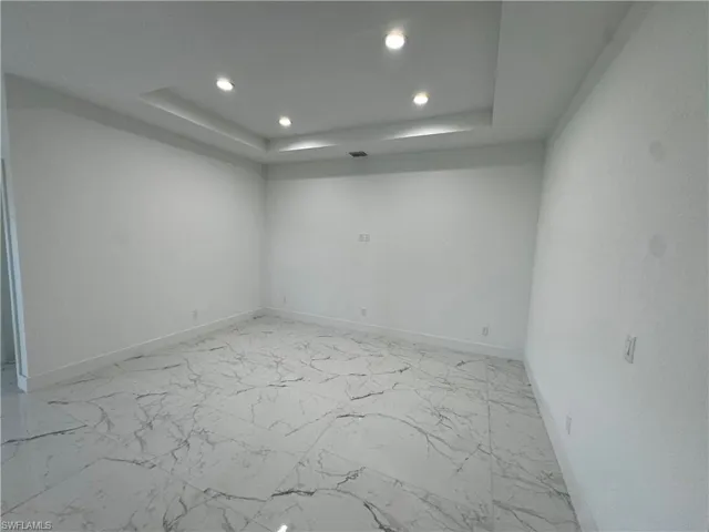 Living room with marble finish floor, baseboards, a raised ceiling, and recessed lighting