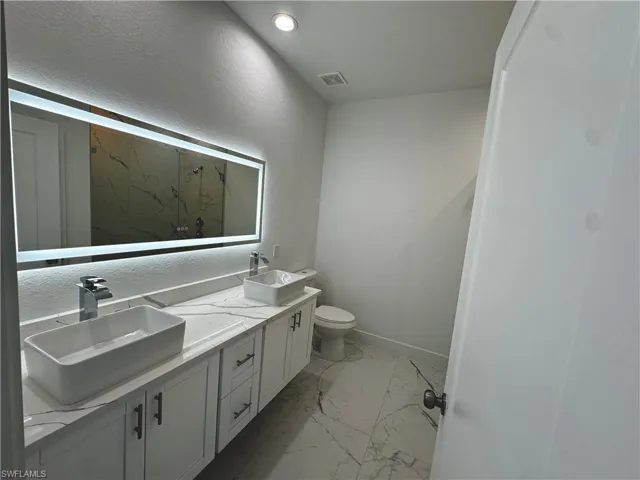 Master bathroom featuring marble finish floor, double vanity, a sink, and visible vents
