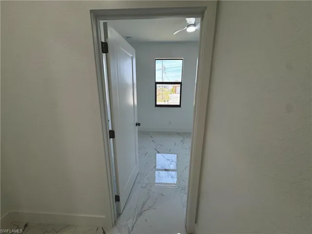 First bedroom doorway with marble finish floor and baseboards