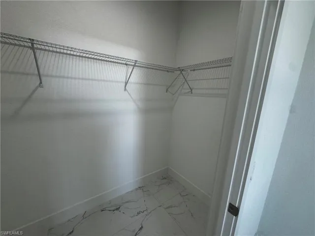 Walk in closet featuring marble finish floor