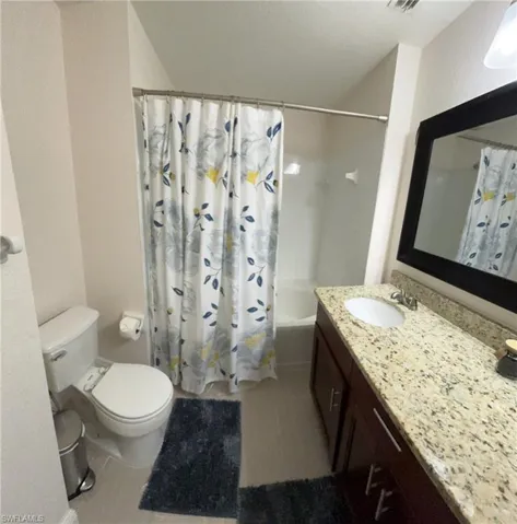 Full bathroom featuring tile floors, toilet, vanity, and shower / bath combo