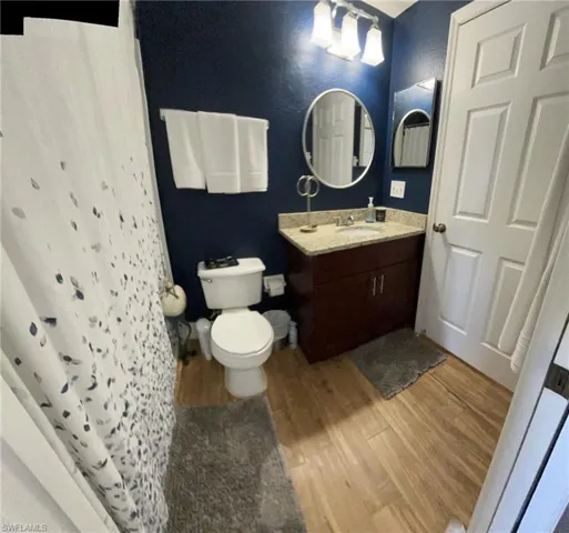 Bathroom with hardwood / wood-style floors, toilet, and large vanity