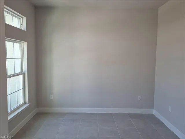 Tiled empty room featuring baseboards