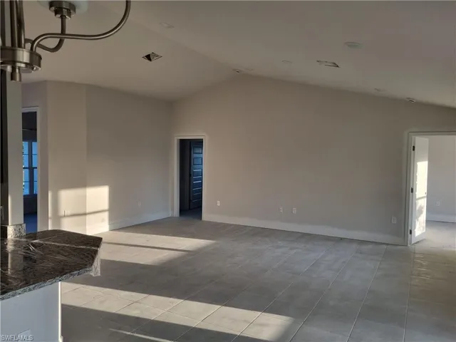 Unfurnished room featuring lofted ceiling and baseboards