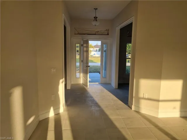 Corridor featuring tile patterned flooring and baseboards