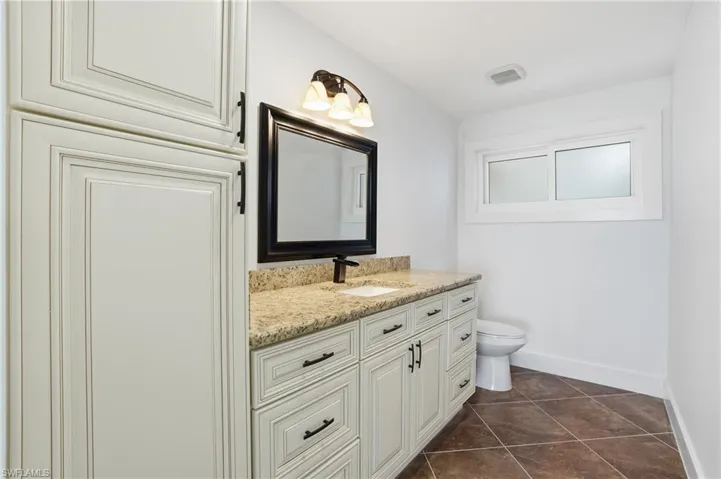 Bathroom with vanity and dark tile patterned flooring - Virtually Edited Image