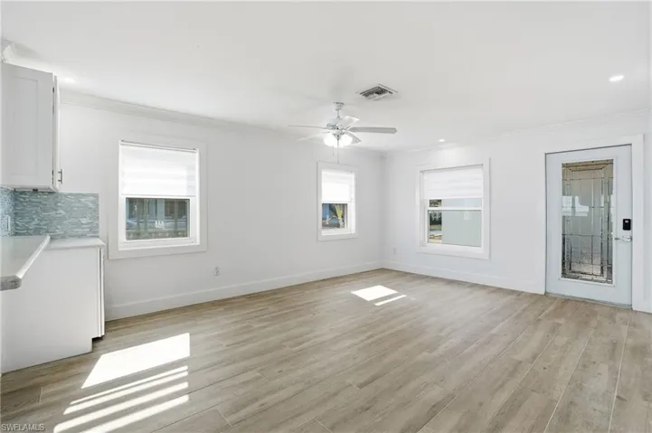 Unfurnished living room with crown molding, light wood-type flooring, a ceiling fan, and recessed lighting - Virtually Edited Image