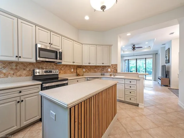 Kitchen featuring appliances with stainless steel finishes, kitchen peninsula, a kitchen island, light tile patterned floors, and ceiling fan