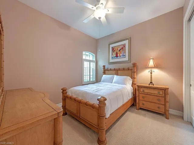 Carpeted bedroom featuring ceiling fan and lofted ceiling
