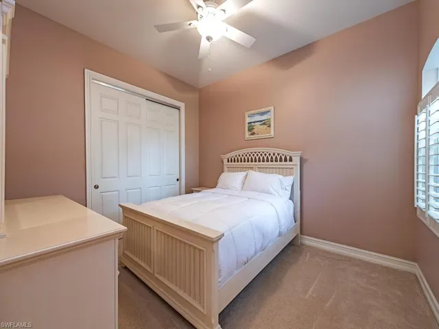 Carpeted bedroom featuring ceiling fan and a closet