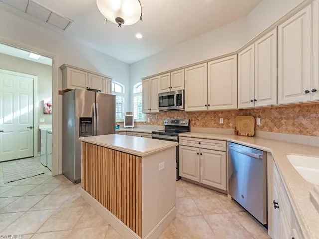 Kitchen featuring a center island, light tile patterned flooring, appliances with stainless steel finishes, and tasteful backsplash