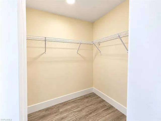 Walk-in closet featuring wood-finish flooring and wall-mounted wire shelving