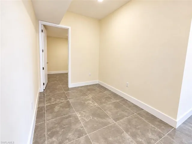 Large-format ceramic tile flooring, neutral wall tones, and interior swing door