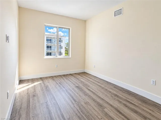 Neutral interior space featuring wood-finish flooring, light-toned walls, and a large window