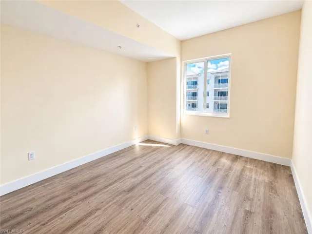 Neutral-toned interior space featuring wood-finish flooring and a single-pane window