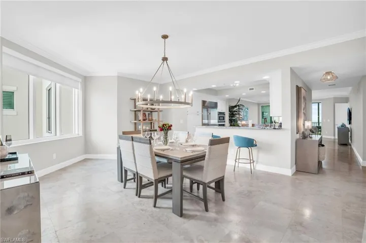 Dining room with ornamental molding, a notable chandelier, and light tile patterned floors
