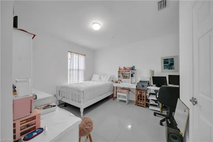 Bedroom with a desk and light tile patterned floors