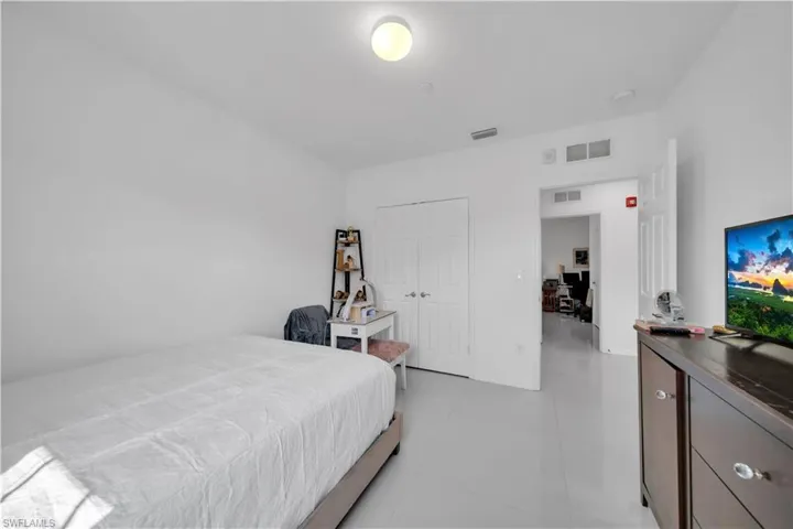 Bedroom with a desk, light tile patterned floors, and a closet