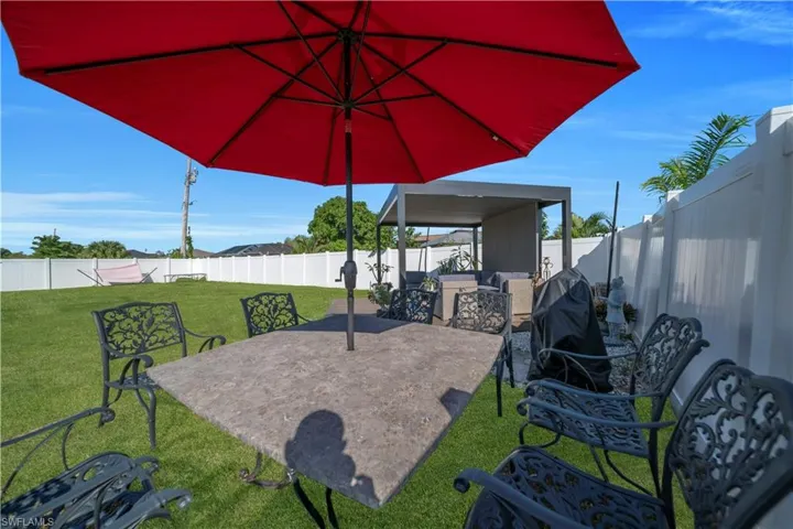 Fenced backyard featuring a patio area and a grill