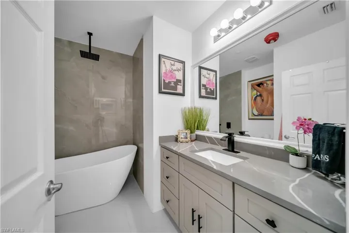 Bathroom with vanity, a freestanding bath, a shower, and light tile patterned floors