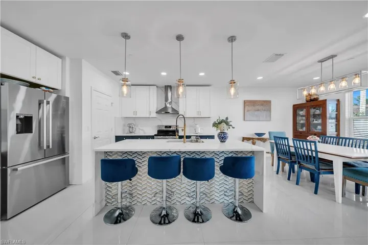 Kitchen with appliances with stainless steel finishes, pendant lighting, a breakfast bar area, light tile patterned floors, and recessed lighting