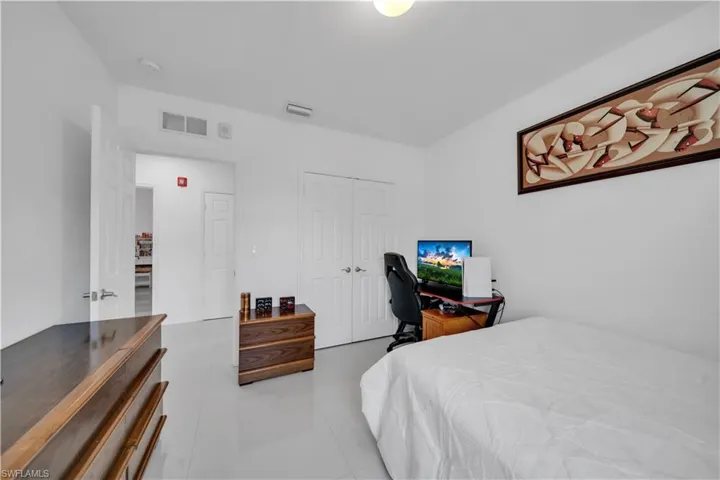 Bedroom featuring an office area, a closet, and light tile patterned flooring