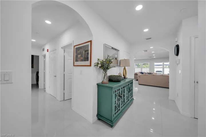 Hall featuring arched walkways, recessed lighting, and light tile patterned floors