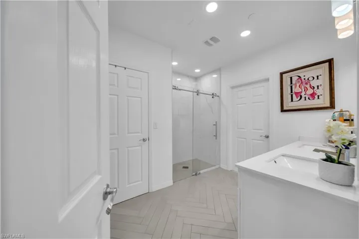 Full bathroom featuring double vanity, a marble finish shower, and recessed lighting