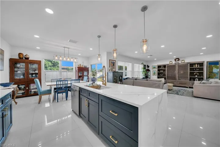 Kitchen with light tile patterned floors, light stone countertops, open floor plan, hanging light fixtures, and recessed lighting
