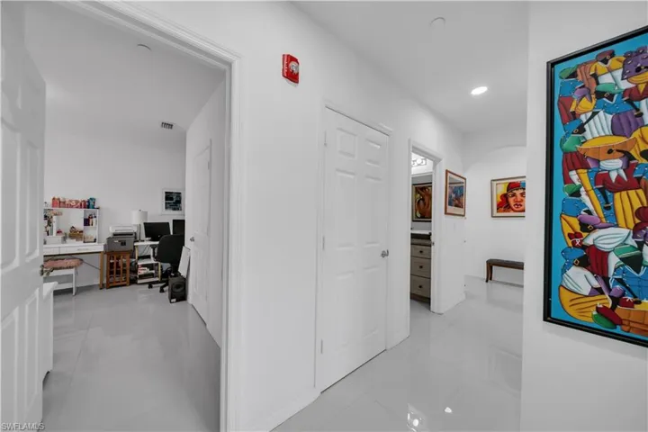Corridor with light tile patterned flooring, a desk, and recessed lighting