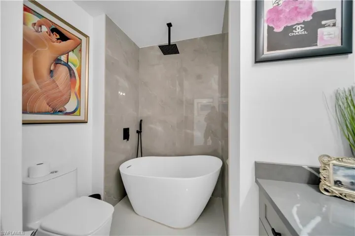 Full bath with a freestanding bath, tiled shower, vanity, and tile walls