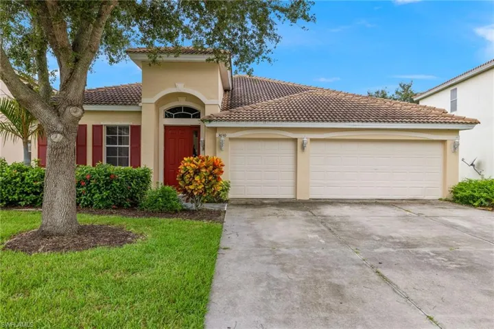 Stucco exterior with a tile roof, featuring a vibrant red entry door with an arched transom window, and a two-car garage with individual doors