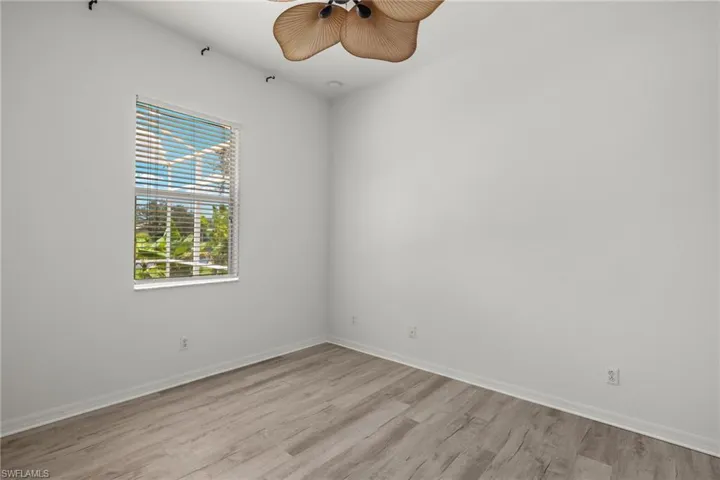 Wood-finish flooring, single window with blinds, ceiling fan, and white walls