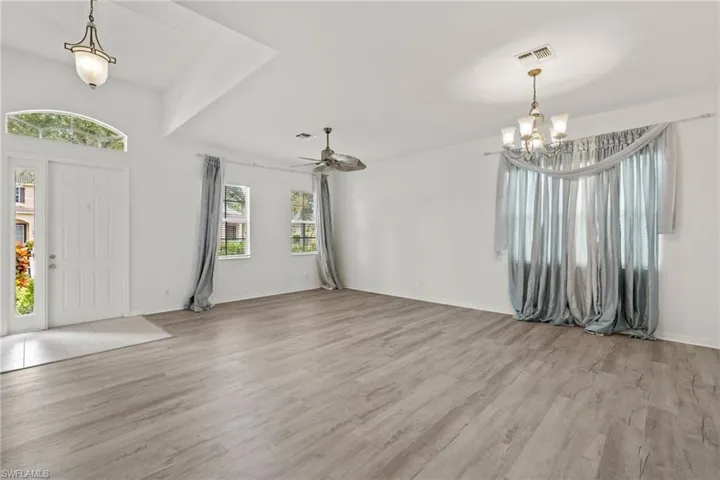 Spacious room featuring wood-finish flooring, vaulted ceilings, and multiple windows