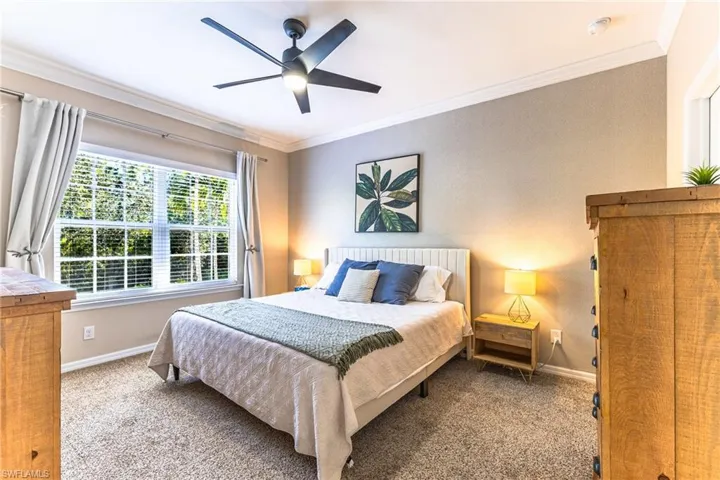 Carpeted bedroom with ornamental molding and a ceiling fan