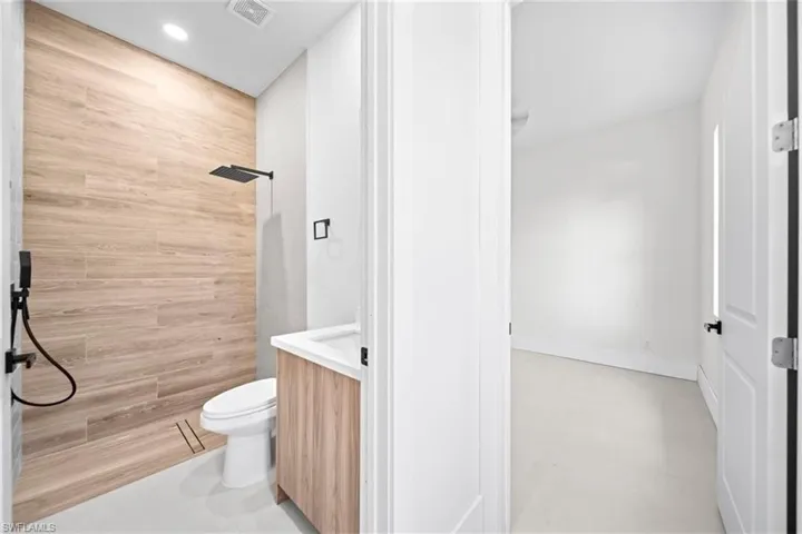 Bathroom featuring vanity, tiled shower, tile walls, and recessed lighting