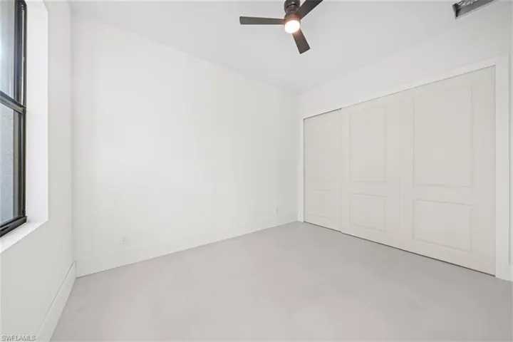 Unfurnished bedroom with finished concrete flooring, a ceiling fan, and a closet