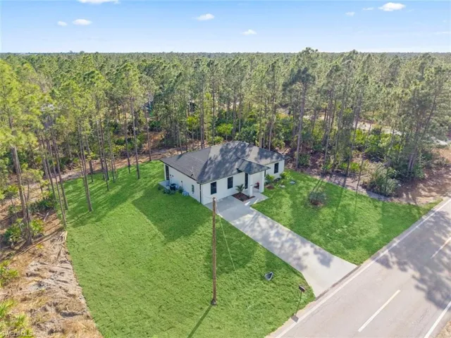 Aerial view of property and surrounding area with a heavily wooded area
