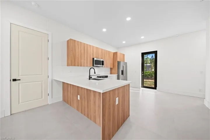 Kitchen featuring modern cabinets, a peninsula, recessed lighting, stainless steel appliances, and light stone countertops
