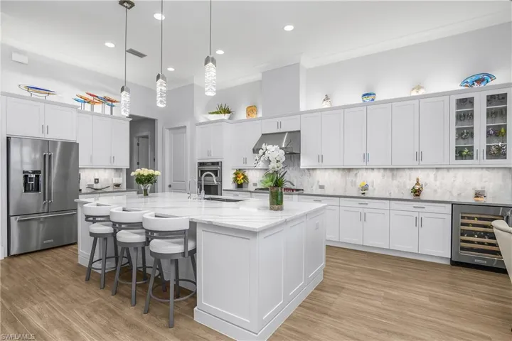 Beverage service area in kitchen features glass upper cabinets and under counter wine cooler.