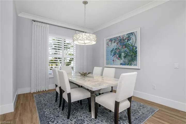 Formal open dining area sits just off the kitchen and features designer lighting, crown molding and plantation shutters.