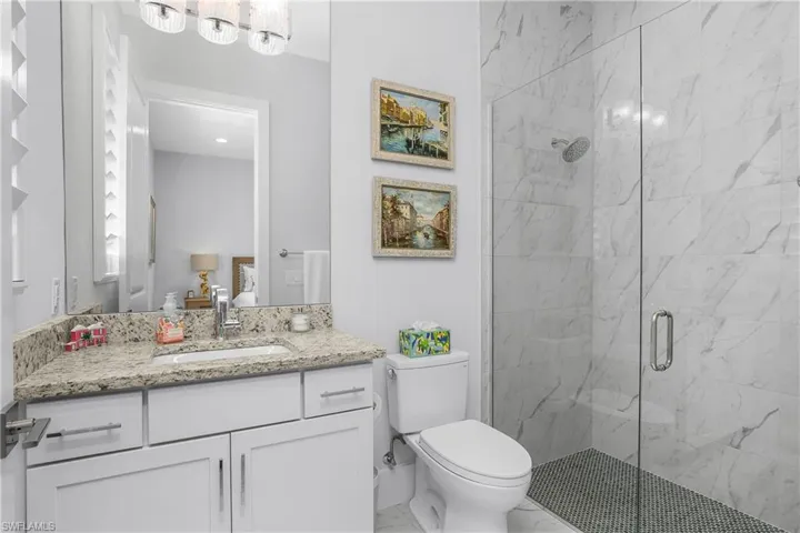 Ensuite guest bath with frameless walk-in shower.