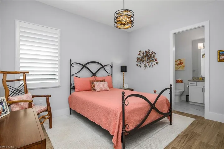 Guest bedroom features plantation shutters, designer lighting and an ensuite bath, providing privacy and comfort for overnight guests.