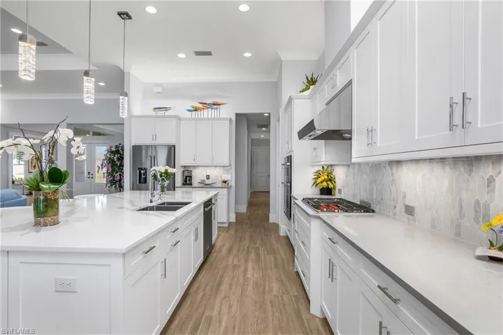 This kitchen is a chef's dream featuring an oversized island with additional storage cabinetry, natural gas cooktop, over/under cabinet lighting, and a spacious walk-in pantry.