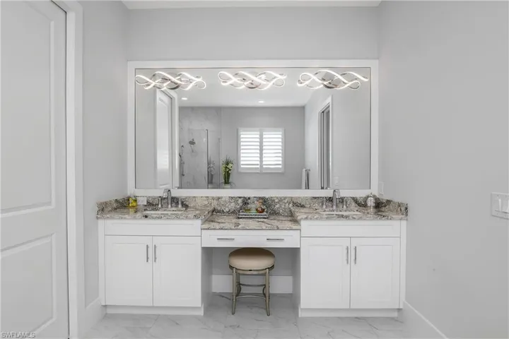 Bath features dual vanities, dual sinks, framed mirror and designer lighting.