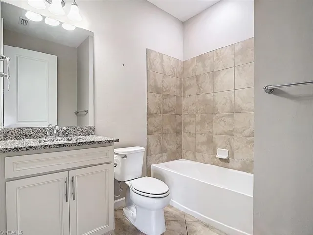 Bathroom with visible vents, washtub / shower combination, toilet, tile patterned floors, and vanity