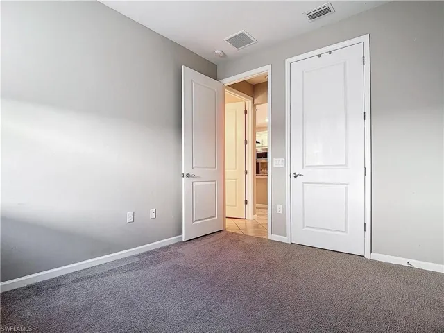Unfurnished bedroom with carpet, visible vents, and baseboards