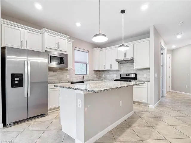 Kitchen featuring under cabinet range hood, a kitchen island, appliances with stainless steel finishes, and white cabinetry